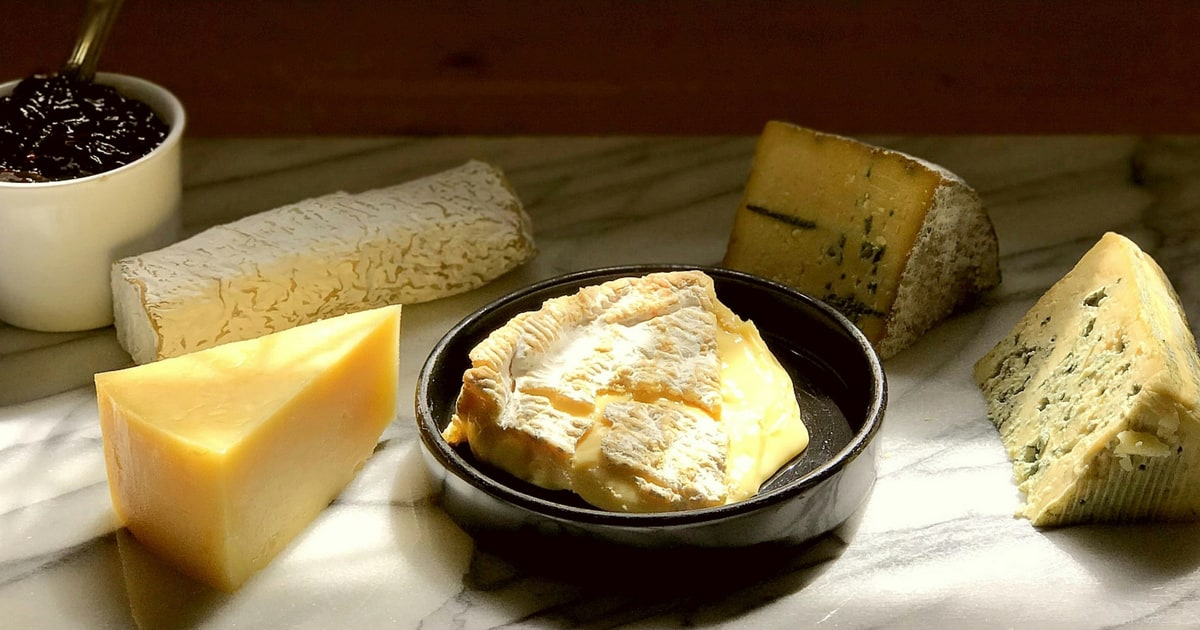 Assorted hard and soft cheeses on a wooden board