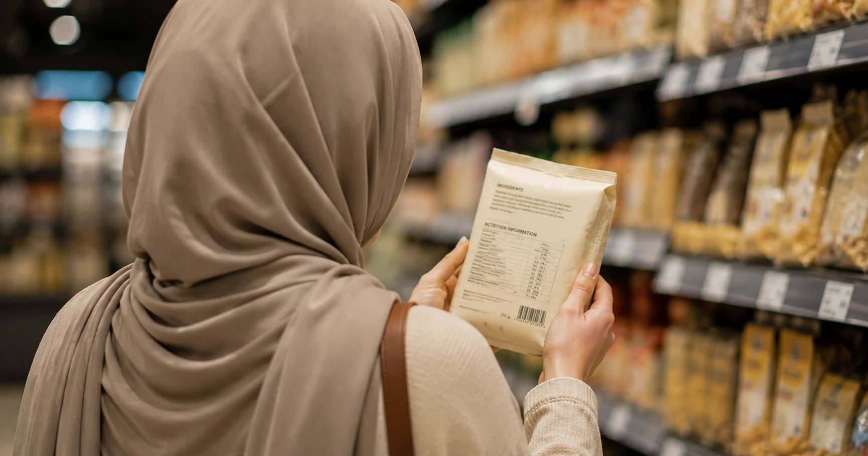 Consumer reading a packaged food label in a supermarket